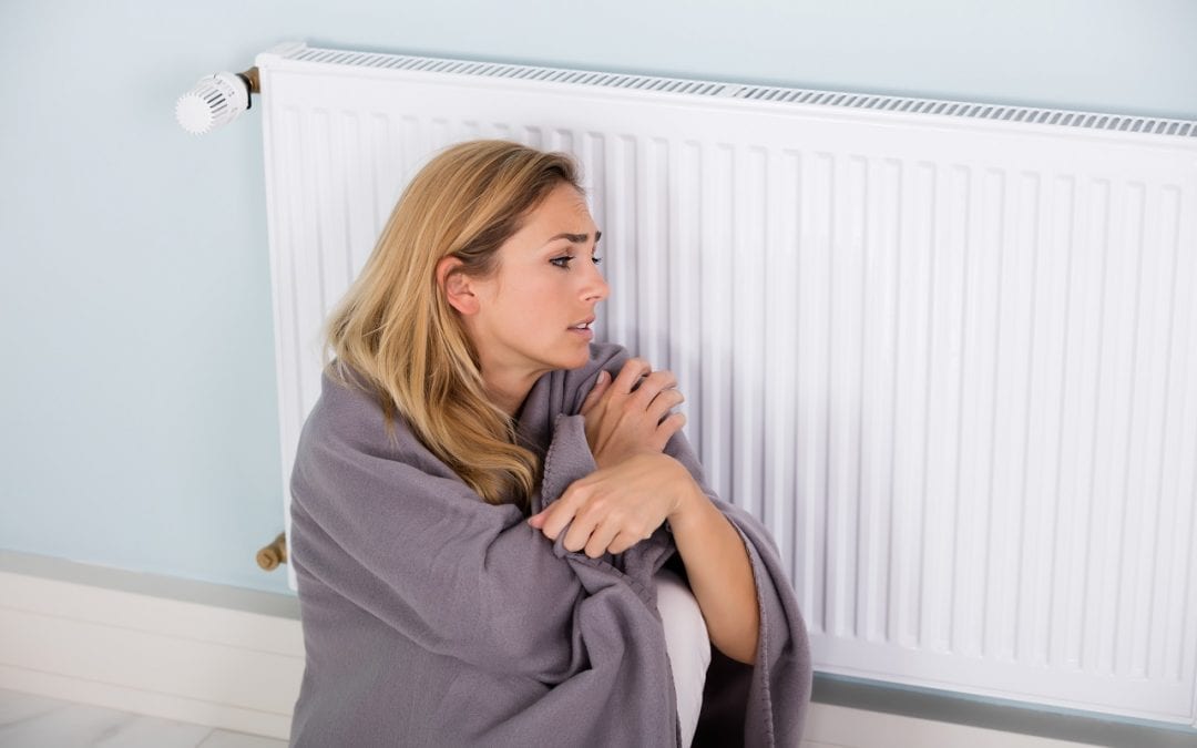 Woman Sitting Near Thermostat for Comfort