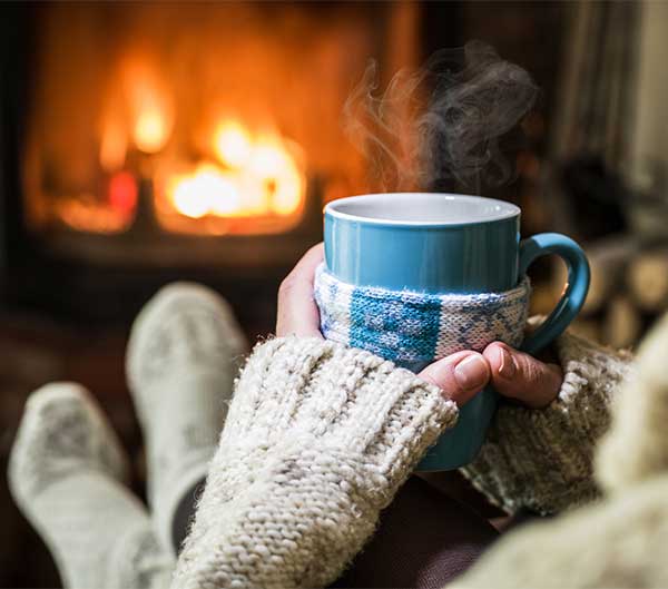 A Woman Sitting Near Room Fireplace Having a Hot Cup of Tea in Her Hands 2